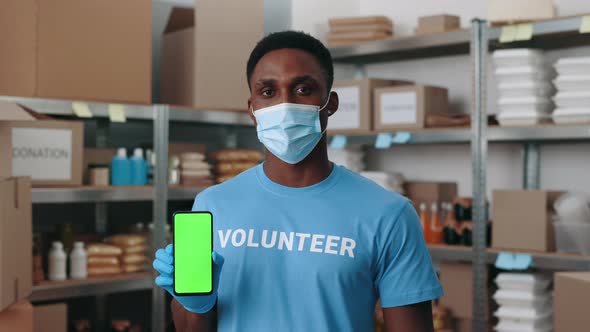 Man in Mask Holding Green Screen Mobile at Food Bank