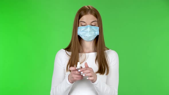 Portrait of Young Girl in Medical Protective Face Mask Looking at Camera and Applying Antiseptic on