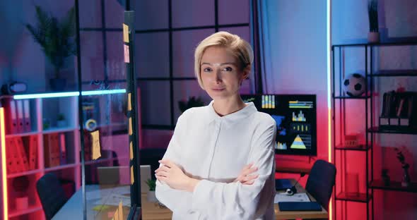 Businesswoman Posing on Camera with Crossed Arms and Confident Face Expression in Evening Office