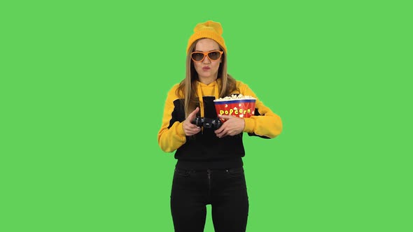 Modern Girl in Yellow Hat, 3D Glasses with Popcorn Is Playing a Video Game Using a Wireless