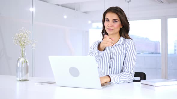 Hispanic Woman Pointing at Camera in Office at Work