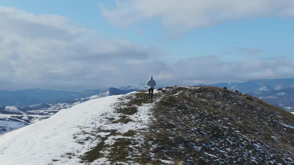 A Man Jogging on an Early Winter Morning Along a Snowcovered Trail on a Hilltop Against the Backdrop