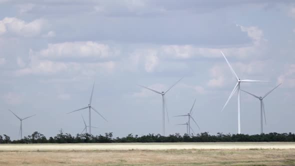 Wind Turbines in the Meadow Produce Alternative Energy Against the Background of the Sky