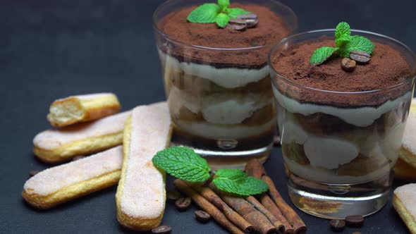 Classic Tiramisu Dessert in a Glass and Savoiardi Cookies on Dark Concrete Background