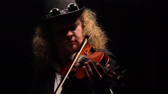 Portrait of Man in an Original Hat in Irish Style Plays Violin on Black Background