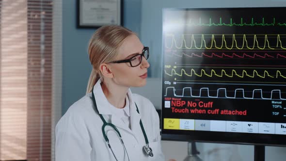 Close-up of Smart Female Cardiologist in Lab Coat Discussing EKG Data with Colleague alt
