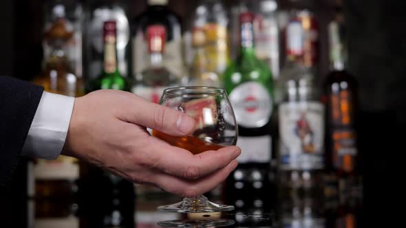 Closeup of a Businessman Holding a Glass of Cognac in a Bar