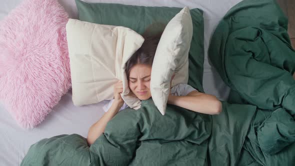 A Young Woman in Bed Tries To Rest Irritated By Noisy Neighbors