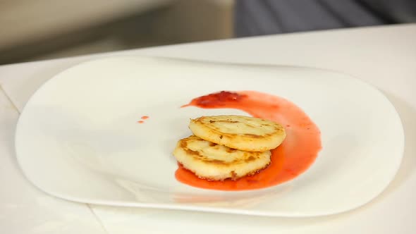 Putting a Portion of Cottage Cheese Pancakes with Berry Jam on a Plate