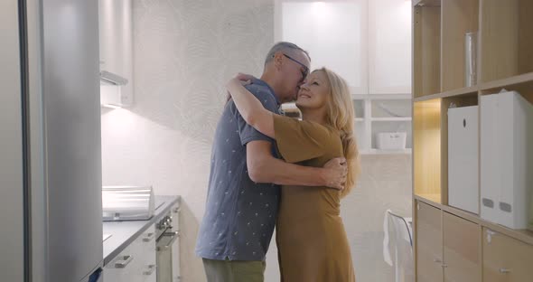 Side View of Senior Couple Hugging in Modern Kitchen