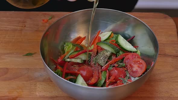 Pouring Olive Oil Into Fresh Summer Salad