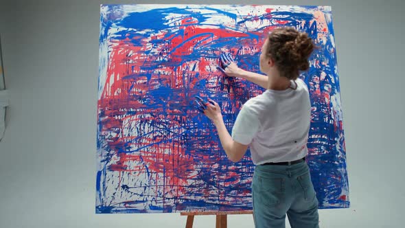 Woman Artist Draws with Her Hands on a Large Canvas in a White Room a Talented Artist Draws a Color