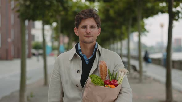 Man Standing on Street and Holding Paper Grocery Bag