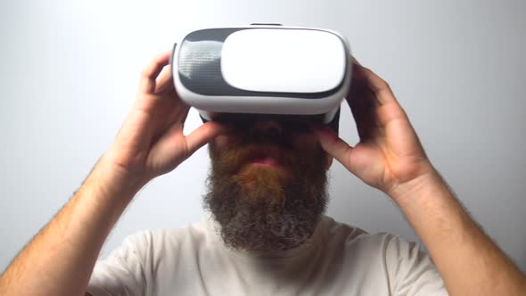 Bearded man use virtual reality headset helmet on white background. VR. Virtual reality glasses.