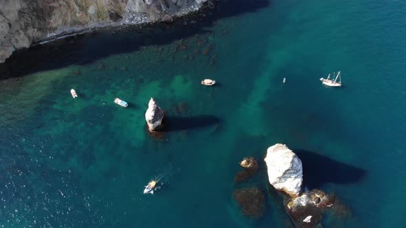 Aerial View of the Rocky Coast of the Bay with Detached Rocks and Boats with Tourists Swimming