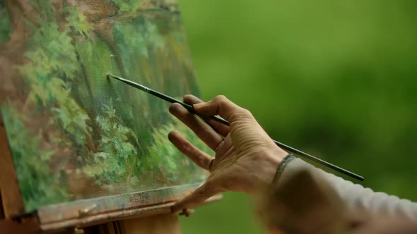 Close-up of a Female's Palm an Artist with a Brush Doing the Finishing Touches Over Painting.