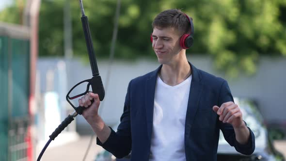 Medium Shot Joyful Man Listening to Music in Headphones Dancing with High Pressure Water Jet in Slow