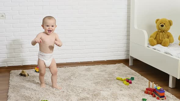 a Baby Boy in a Disposable Diaper Takes the First Steps Barefoot