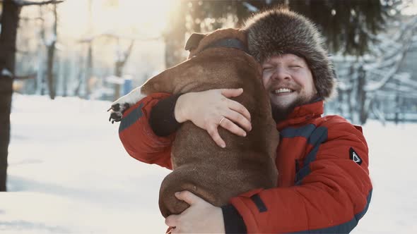 Happy Bearded Man Hugging His Bulldog at Winter Sunny Day