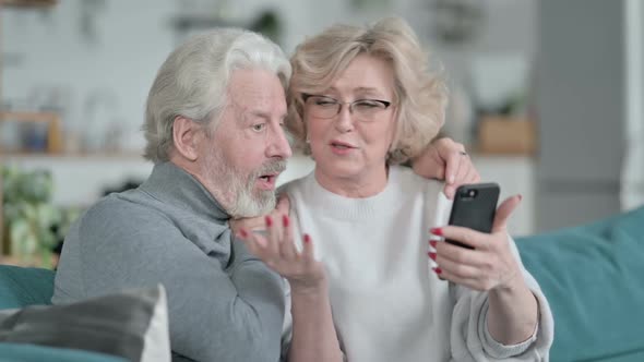 Happy Old Couple Using Smartphone Together at Home