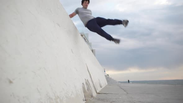 Young Caucasian Male Gymnast Jumping From Wall and Doing Back Somersault Using Thrusting Off the