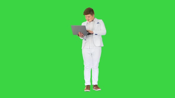 Caucasian Boy in a Suit Working on Laptop on a Green Screen Chroma Key
