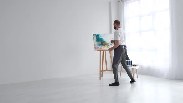 The Artist Paints an Abstract Picture He is Focused on Work Painting on an Easel in His Art Studio