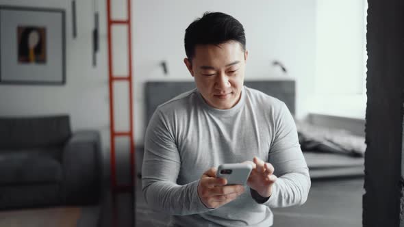 Pretty Asian man texting by phone
