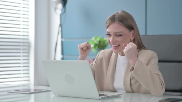 Businesswoman Celebrating Success While Using Laptop in Office