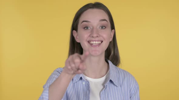Young Woman Inviting Customers with Both Hands on Yellow Background