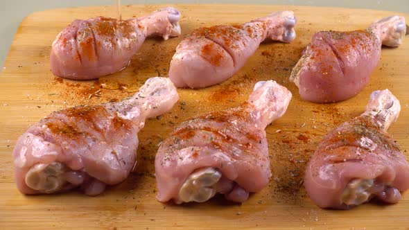 Chicken legs are sprinkled with olive oil on a cutting board. The process of marinating meat.