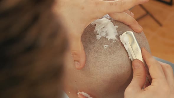 Close-up View of Barber Shaving Head of Male Customer with Razor