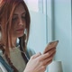 Young woman with red hair, freckles and piercing using a smartphone and headset - VideoHive Item for Sale