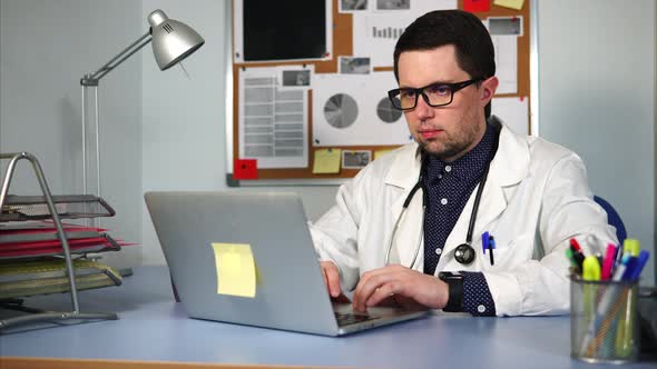 A Therapist with a Stethoscope Treats Patients in His Office Using a Laptop