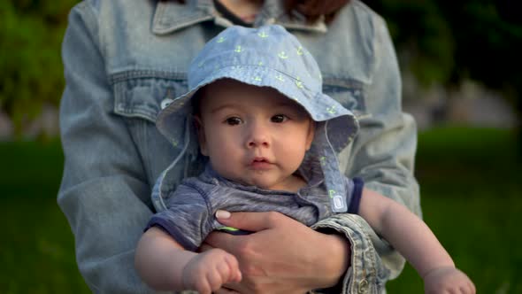 Baby in the Arms of Mom on a Walk Closeup