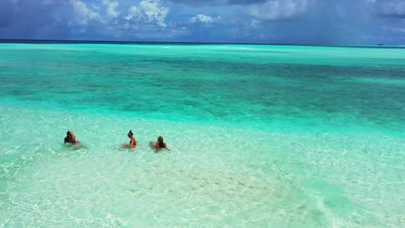 Women sunbathing on idyllic seashore beach journey by aqua blue water with white sand background of 