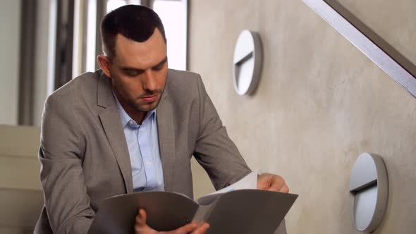 Businessman with Folder Sitting on Stairs 69