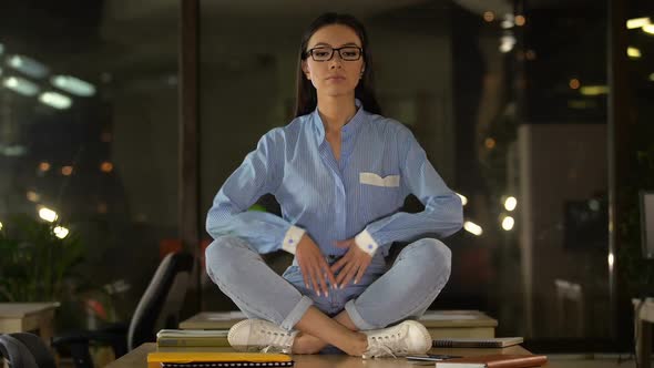 Woman Meditating in Lotus Pose on Office Desk, Relaxation at Work, Productivity