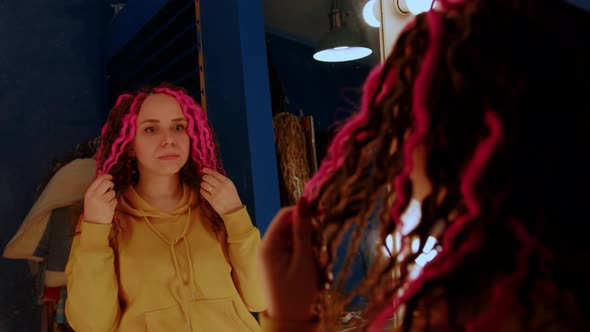 Young Woman Looking in Mirror Considering Her New Hairstyle