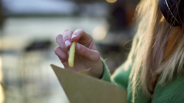 Woman Eating French Fries Outdoors on Winter Street Fair with Ketchup