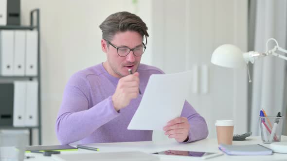 Middle Aged Man with Documents Celebrating Success