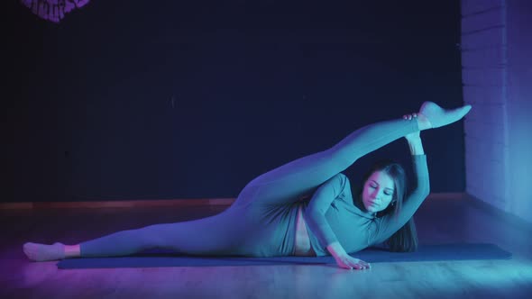 Young Woman Stretching Her Leg in Neon Lighting