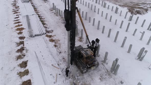 Aerial drone view of a pile bore machine at work at winter construction site 03