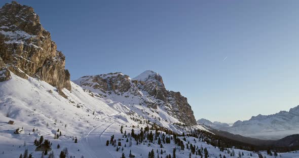 Forward Aerial to Snowy Valley with Woods Forest and Ski Track at Falzarego Pass