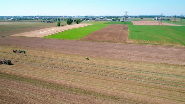 Amish Farm Worker Harvesting the Fields with old and New Equipment