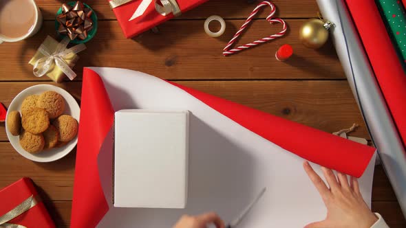 Hands Wrapping Christmas Gift Into Paper at Home