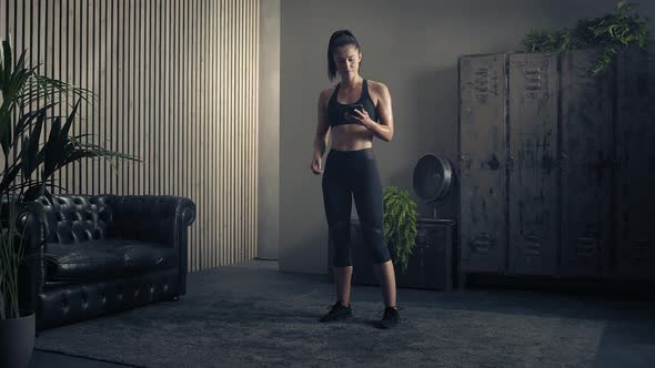 Woman Using Smart Phone with Personal Trainer Workout App at Home. Woman Preparing for Workout Using