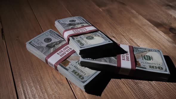 Three Stacks of 10000 American Dollars Banknotes in Bundles Lie on Wooden Table