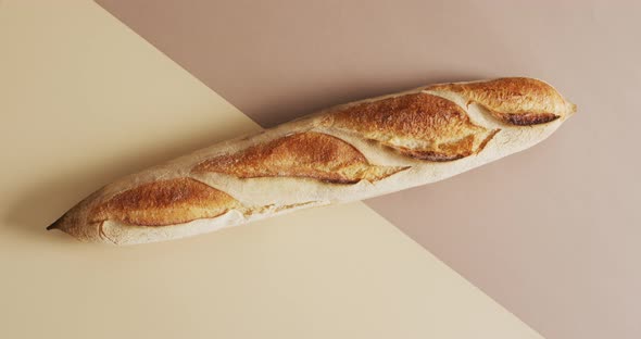 Video of one baguette on a brown and beige surface