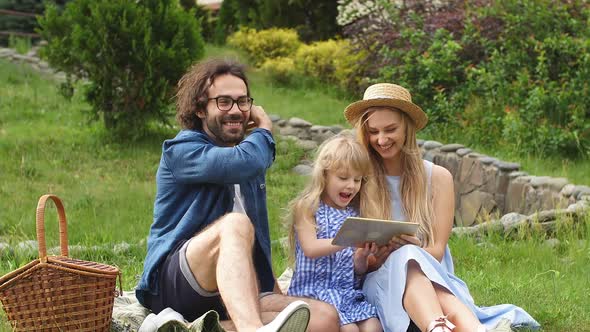 Family Using Digital Tablet During Picnic at Countryside